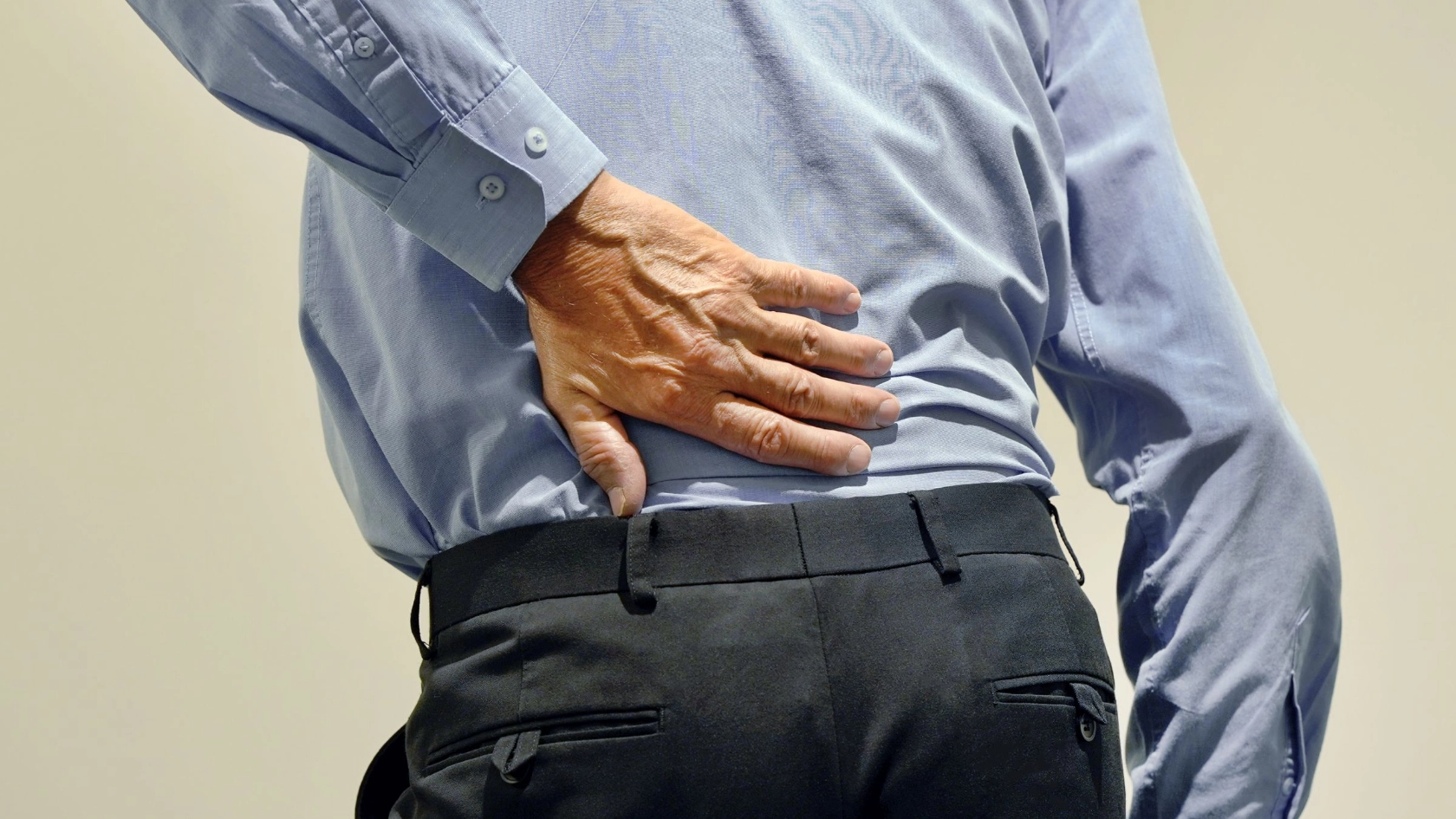 älterer Mann greift sich vor Schmerzen an den Rücken