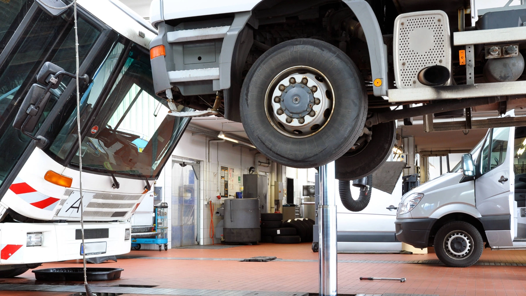 Ein Lkw auf einer Hebebühne. Ein Lieferwagen im Hintergrund.