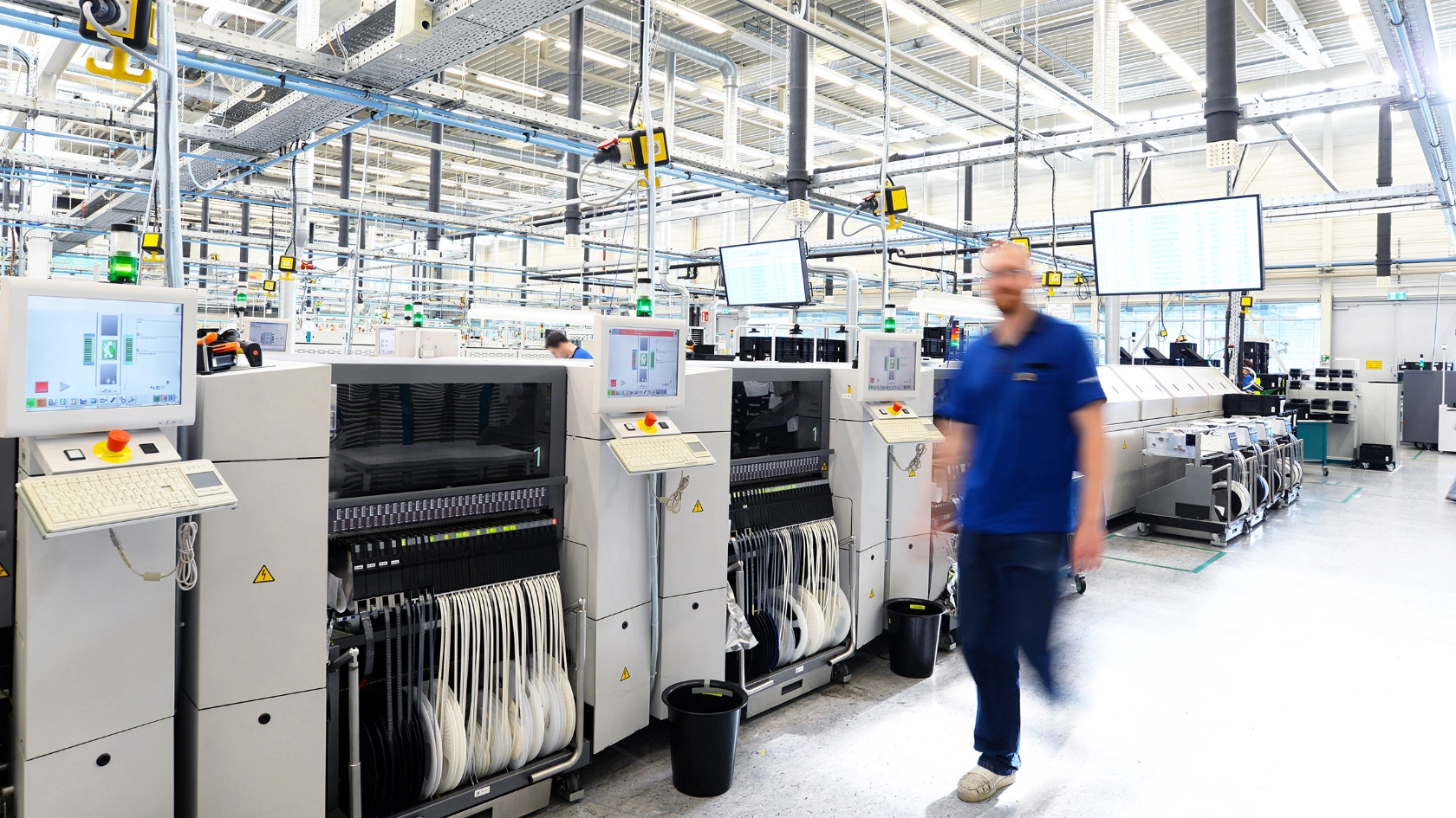 Ein Beschäftigter bedient Maschinen in einer Hightech-Fabrik über einen Monitor