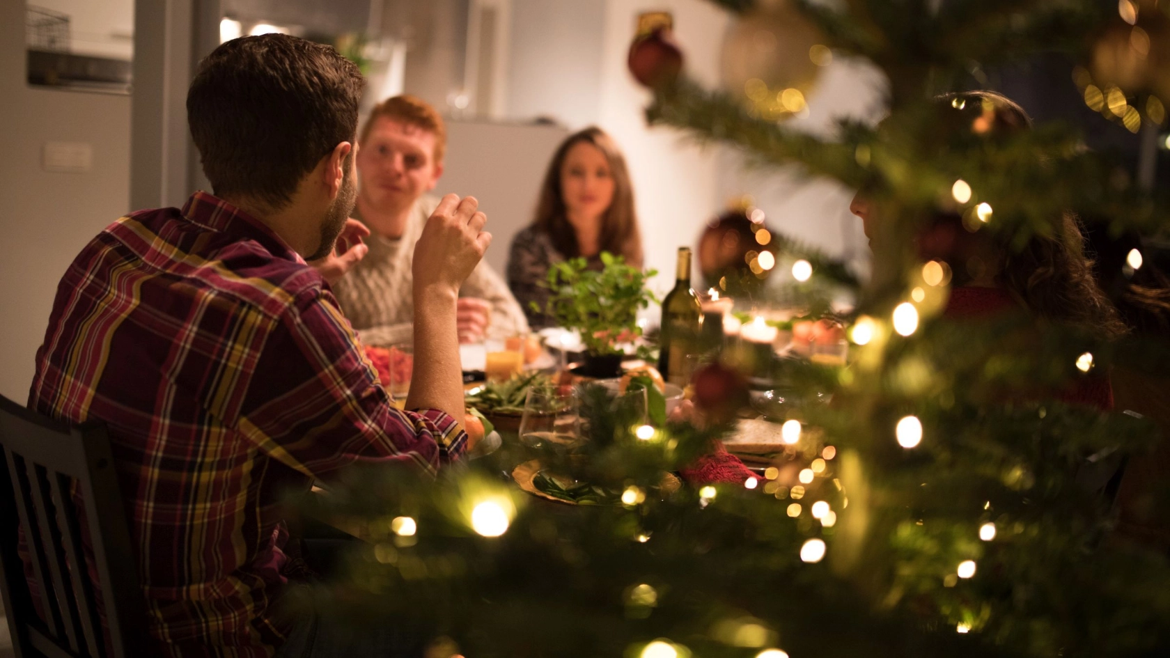 Personen sitzen während der Weihnachtszeit zum Essen an einem Tisch