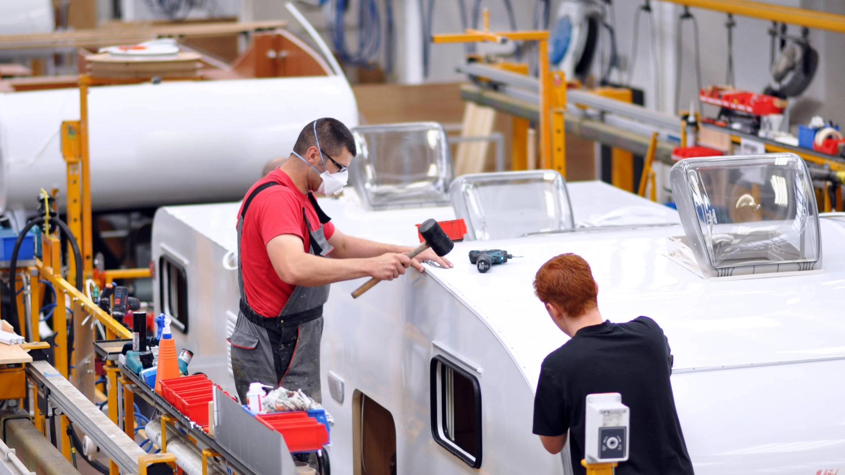 Zwei Männer arbeiten am Dach eines Wohnmobils.