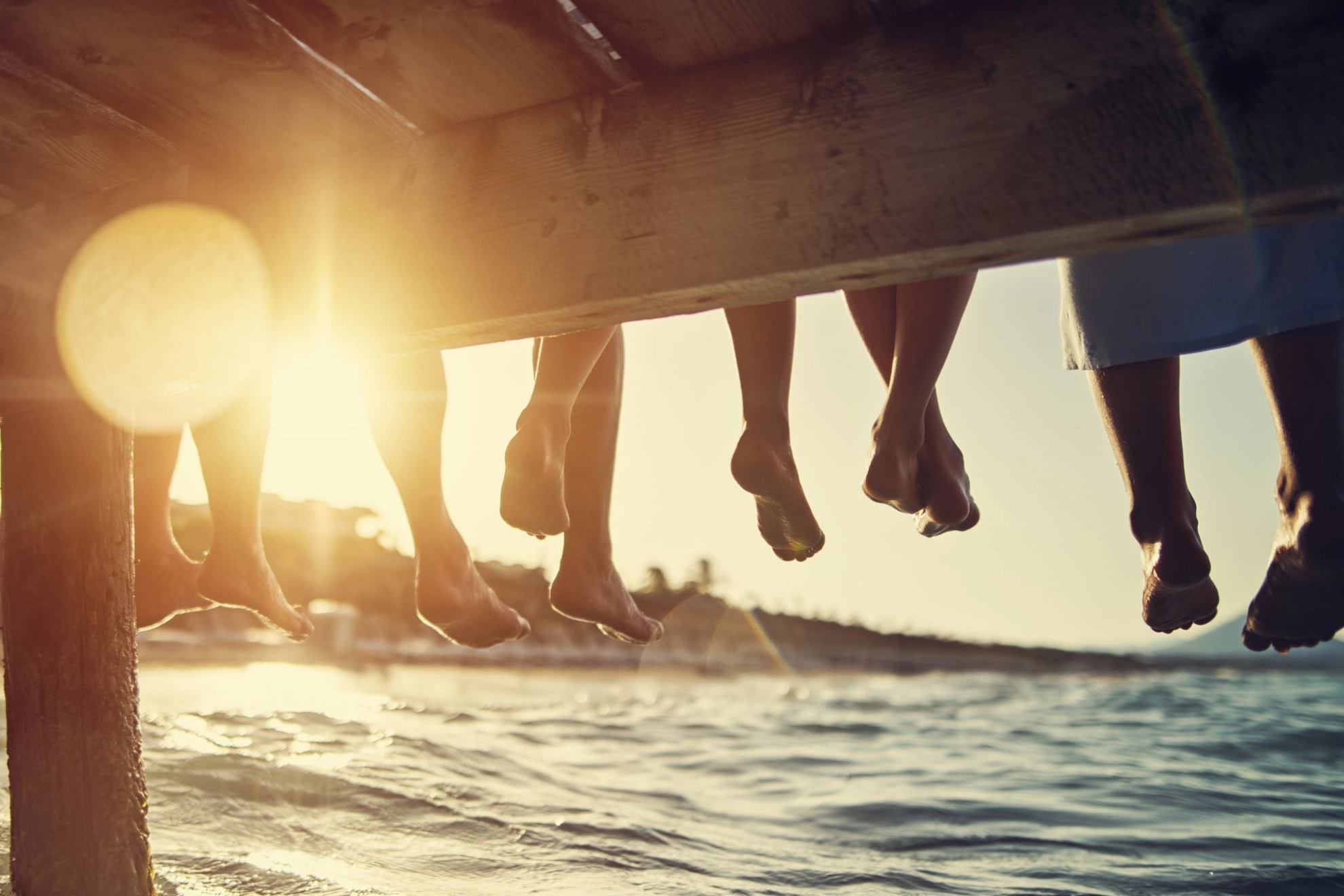 Familie sitzt bei Sonnenuntergang am Pier am Meer