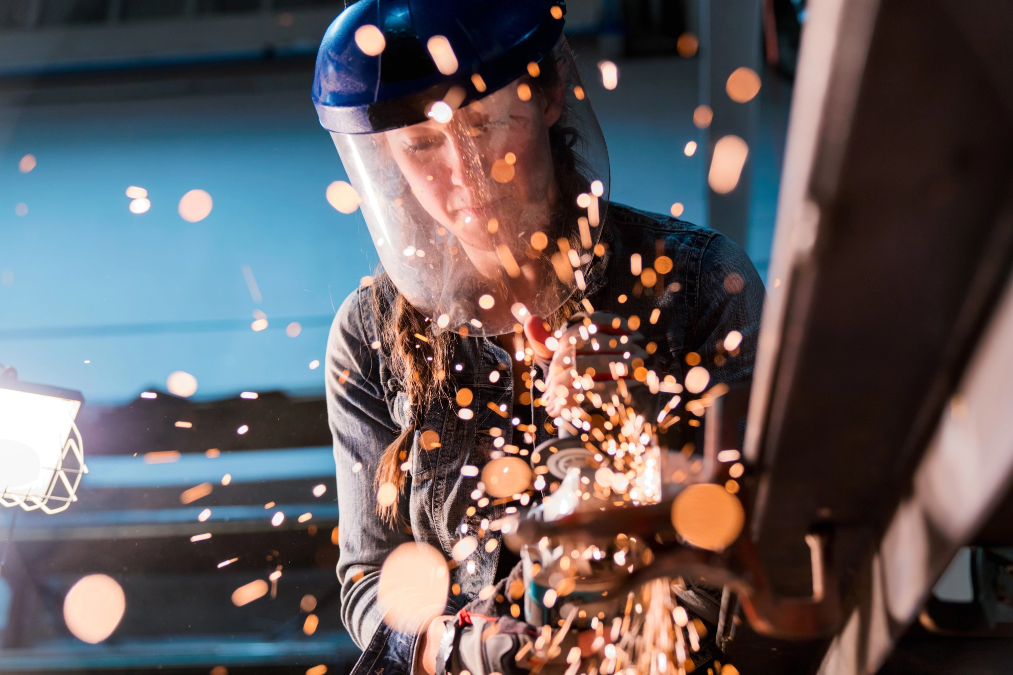 Eine Handwerkerin arbeitet mit einem Winkelschleifer in einer Werkstatt