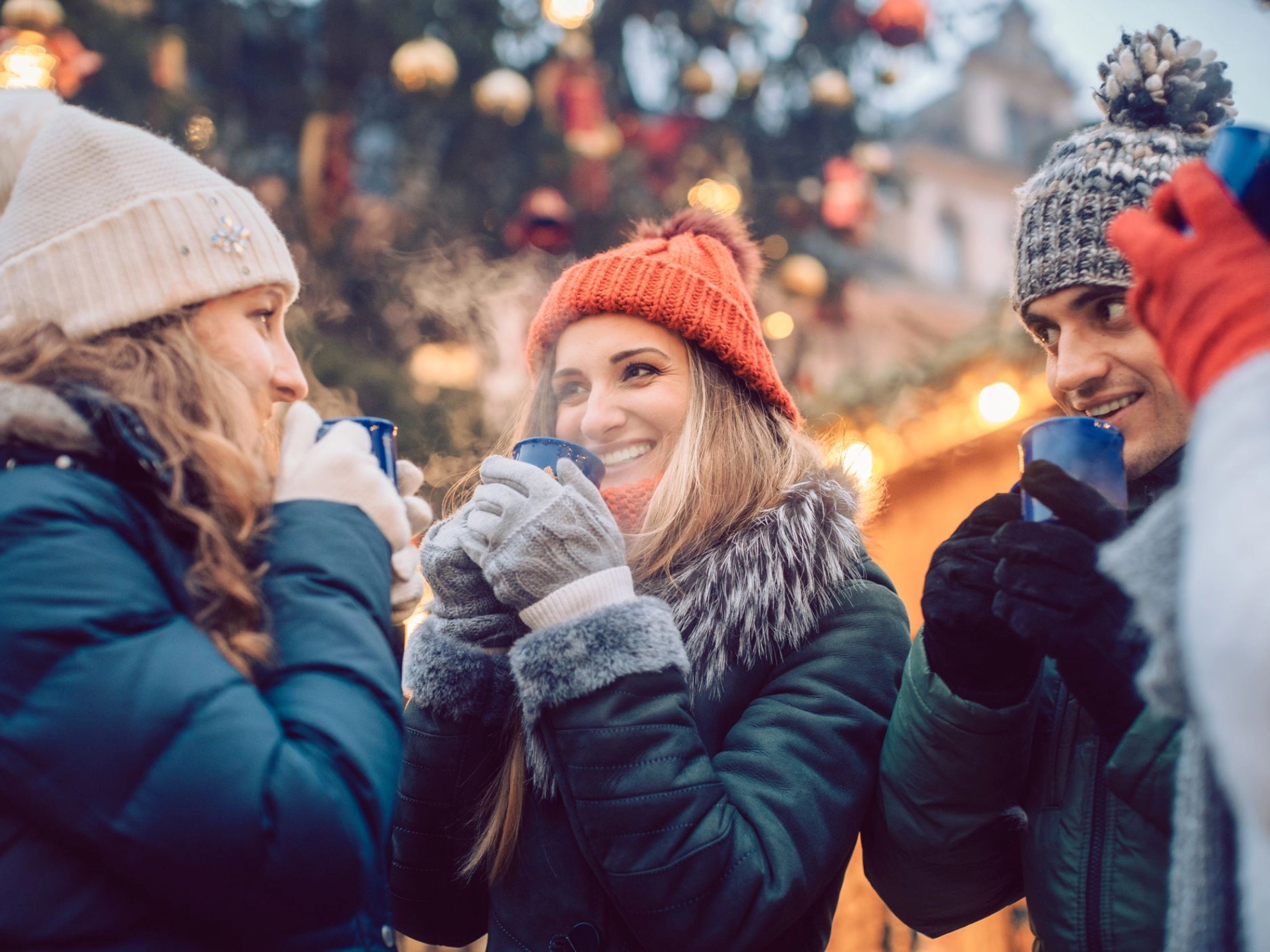 Group of friends drinking mulled wine in the cold on a Christmas Market with fun and laughter