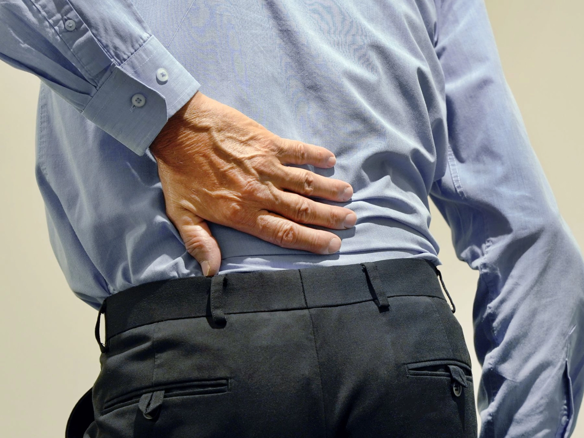älterer Mann greift sich vor Schmerzen an den Rücken