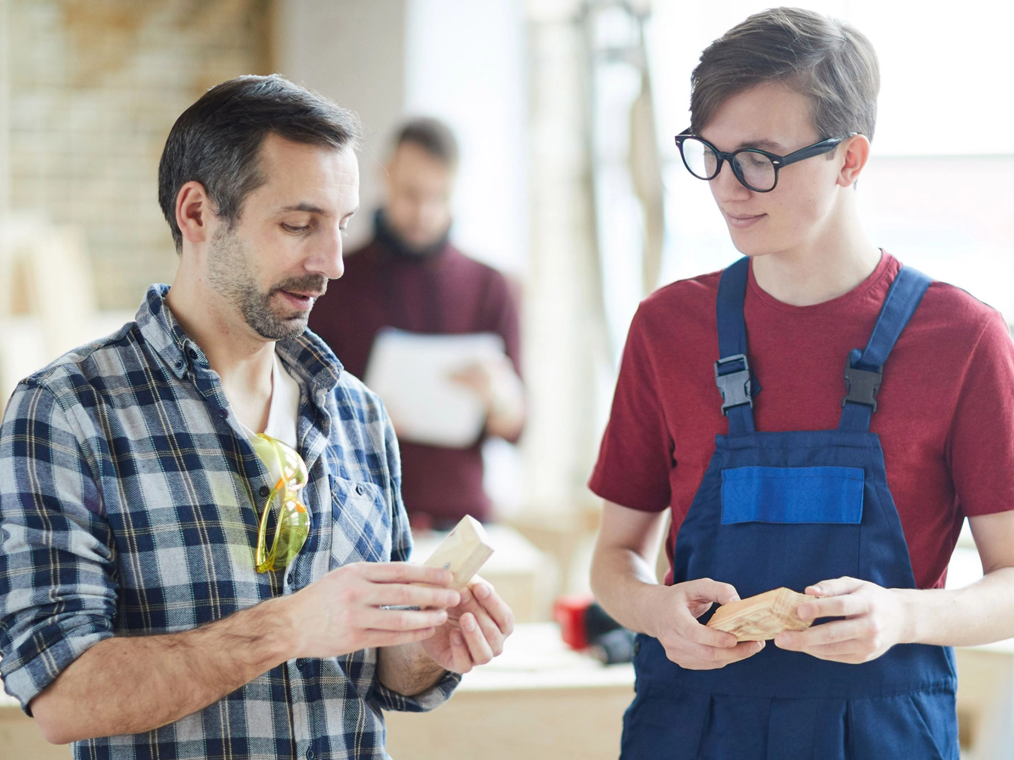 Auszubildender und Meister im Gespräch in einer Schreinerwerkstatt