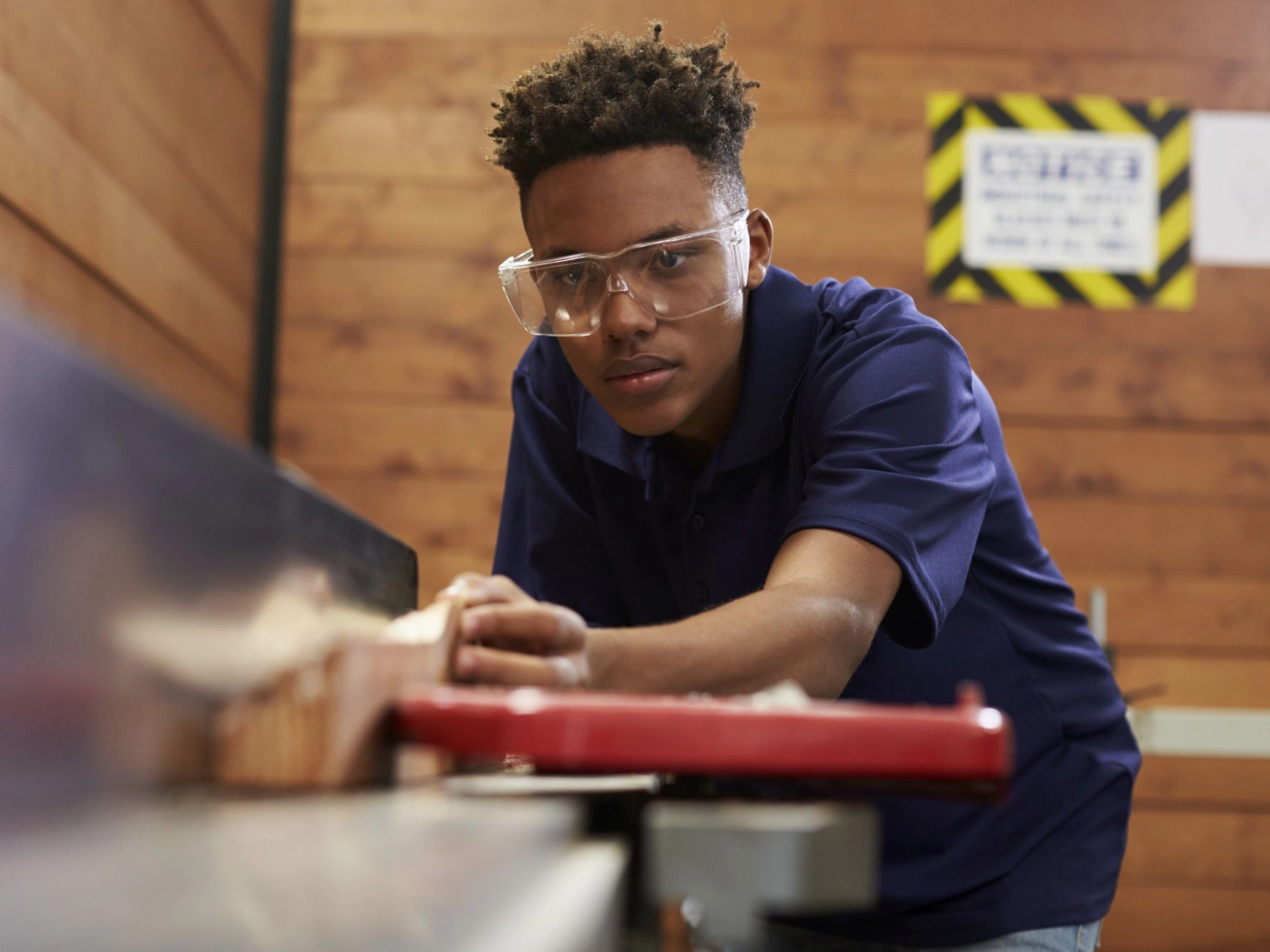 Junger Mann arbeitet in einer Werkstatt mit Holz