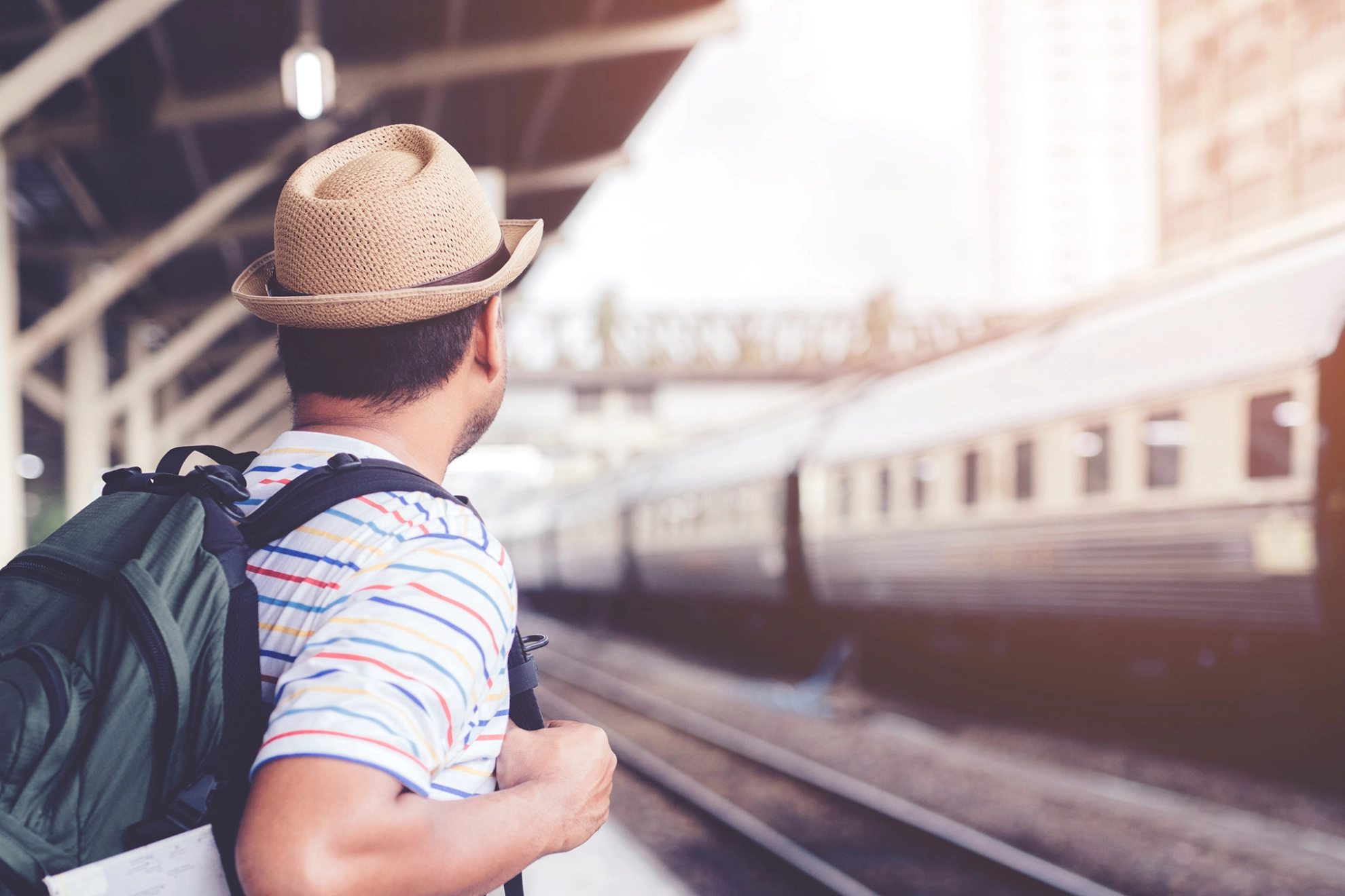 Junger Mann mit einem Rucksack warten auf dem Zug 