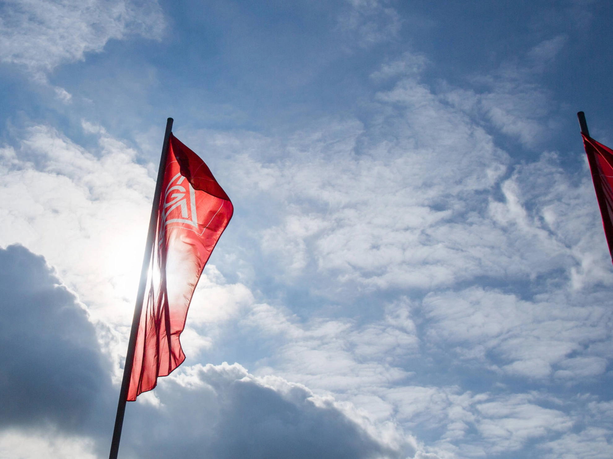 IG Metall-Fahnen vor leicht bewölktem Himmel.