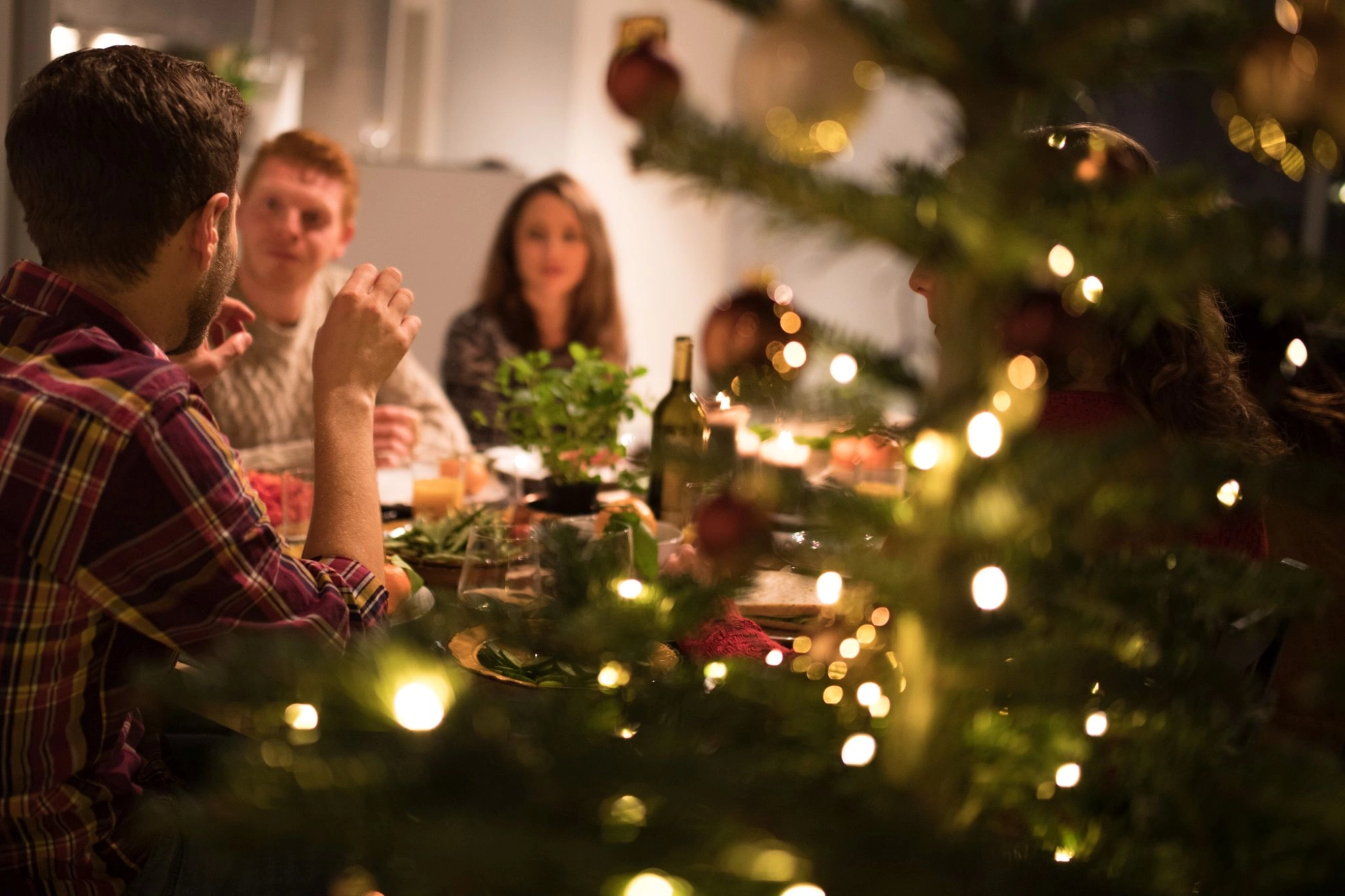 Personen sitzen während der Weihnachtszeit zum Essen an einem Tisch