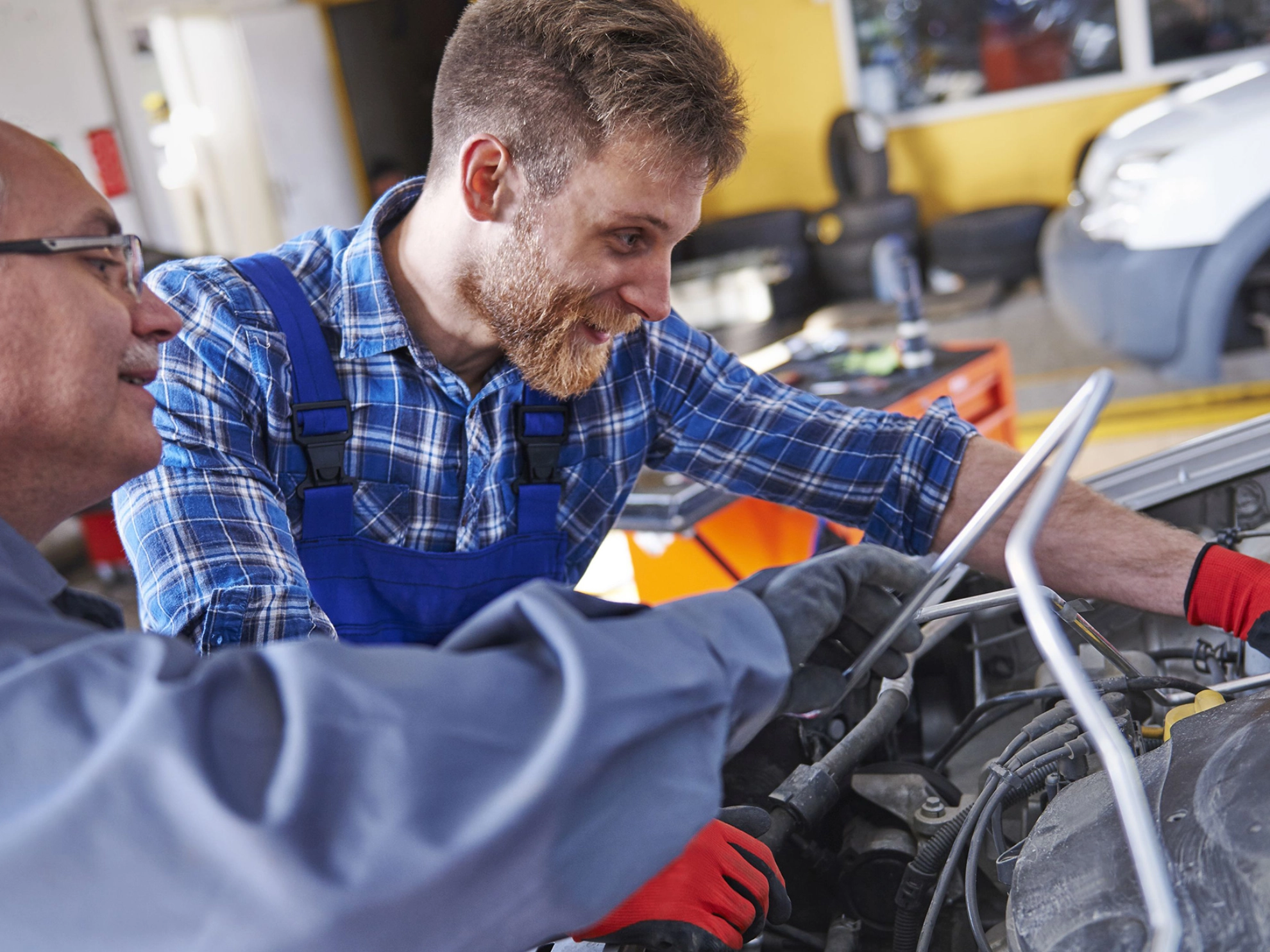 Zwei Kfz-Mechatroniker inspizieren den Motor eines Autos