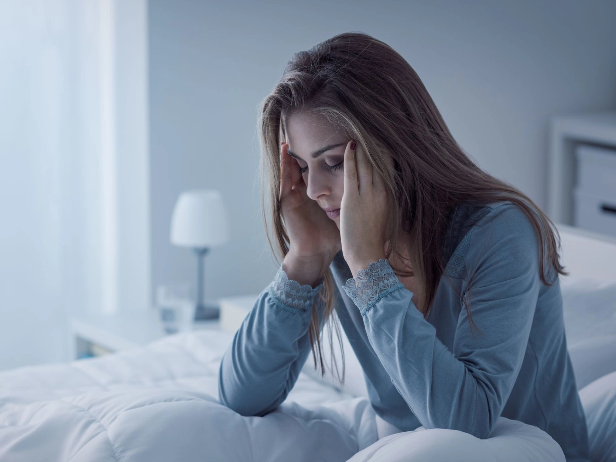 junge Frau sitzt müde in ihrem Bett